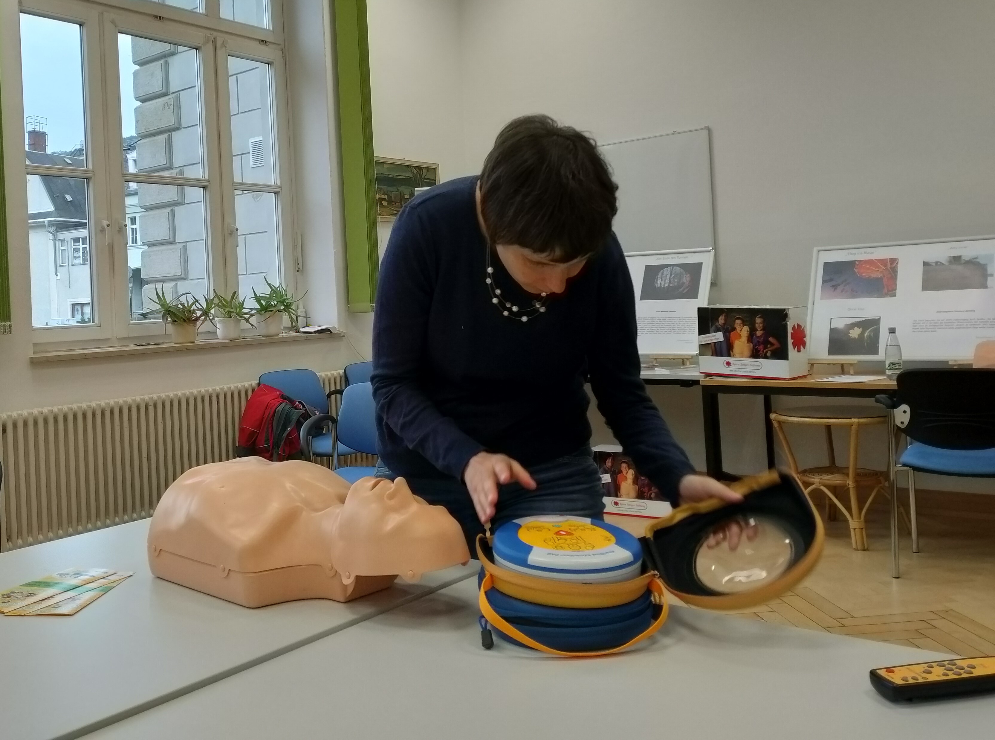 Eine blinde Frau ertastet den Automatisierten externen Defibrillator (AED) vor der Anwendung.