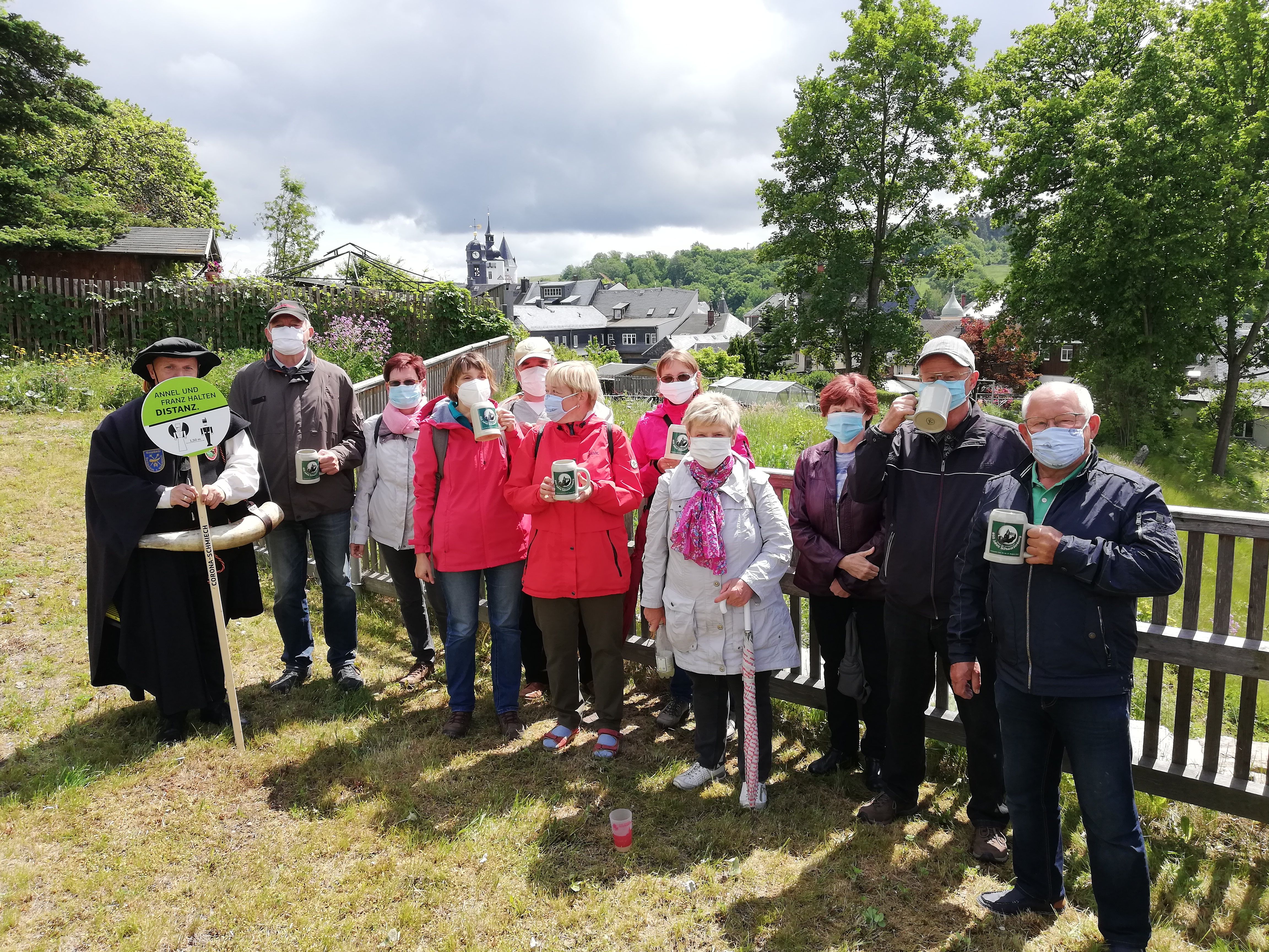 Die Wanderleit mit einem Bierkrug in der Hand bei der Stadtführung mit dem Türmer von Schwarzenberg - Da Corona mit Maske.